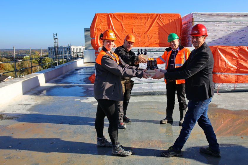 Two representatives of the construction workers (left) receive a case with roof tile beer from Eric Van der Meer (Project leader WUR-FB) and Arie Aalbers (building engineer LIAG).